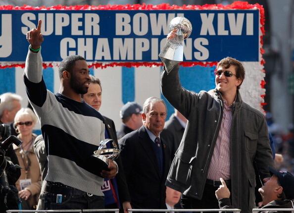 Quarterback Eli Manning (R) of the New York Giants and Super Bowl XLVI MVP holds the Vince Lombardi Trophy as Justin Tuck (R) of the New York Giants looks on during the Giants' Victory Parade on February 7, 2012 in New York City.