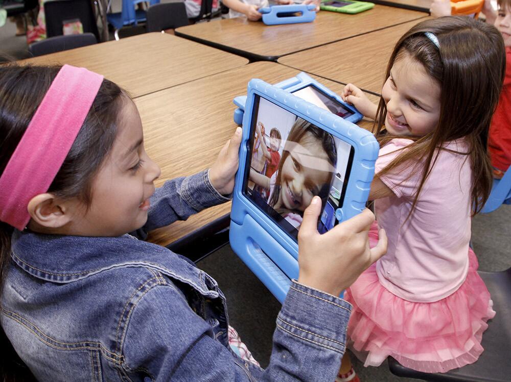First grader Lexi Frost, left, takes a photo of her friend Kate Cooper, right, during class at Palm Crest Elementary School's iPad Learning Lab in La Canada Flintridge on Tuesday, April 8, 2014. The school district recently opened 3 elementary school iPad Learning Labs with donations from the Educational Foundation.