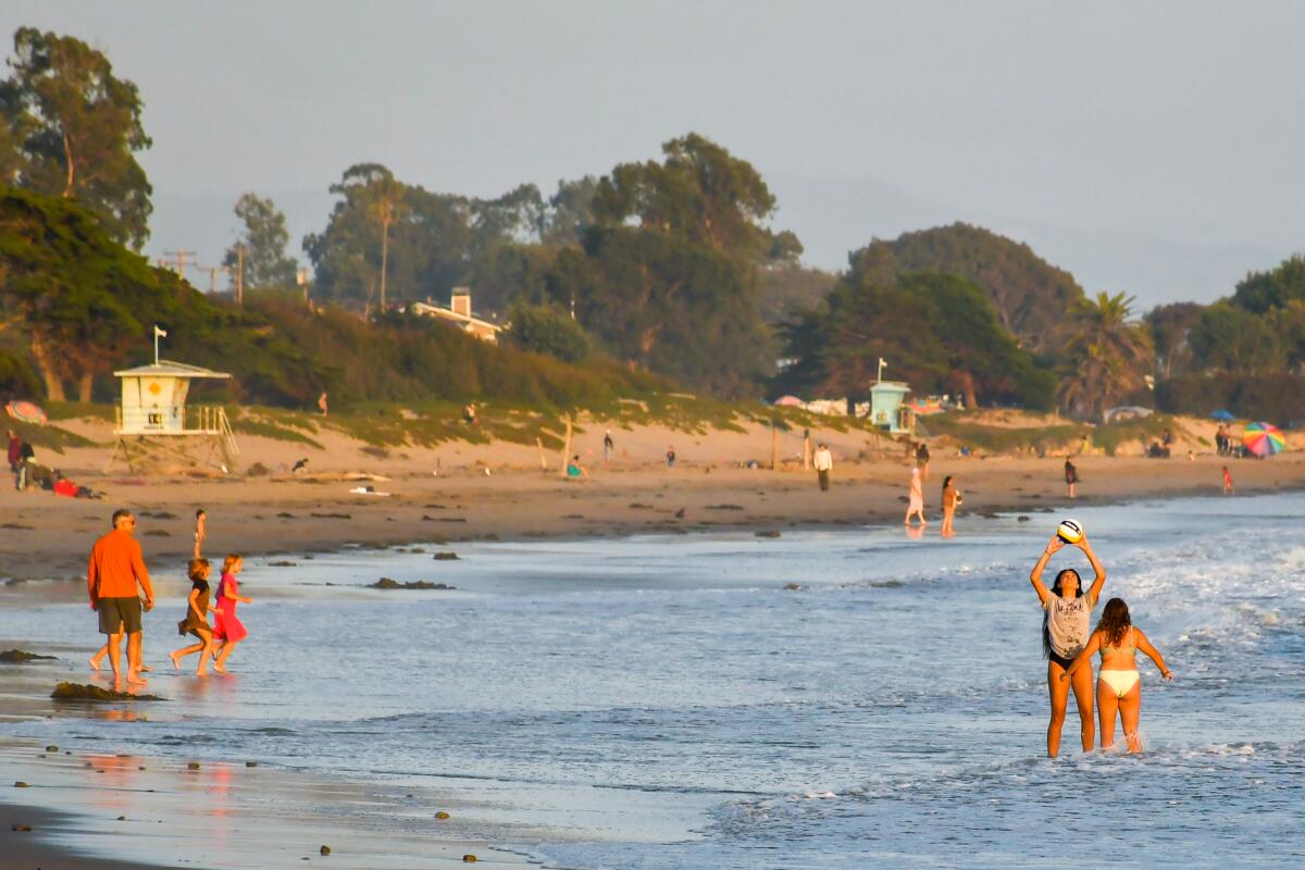 People frolic in the water at Carpinteria State Beach.