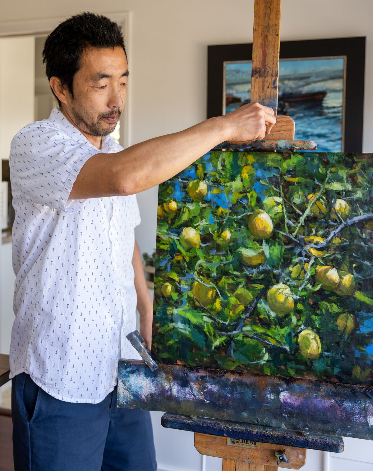 Artist Pil Ho Lee sets one of his favorite pieces of a lemon tree on his easel, at his home in Orange on Wednesday.