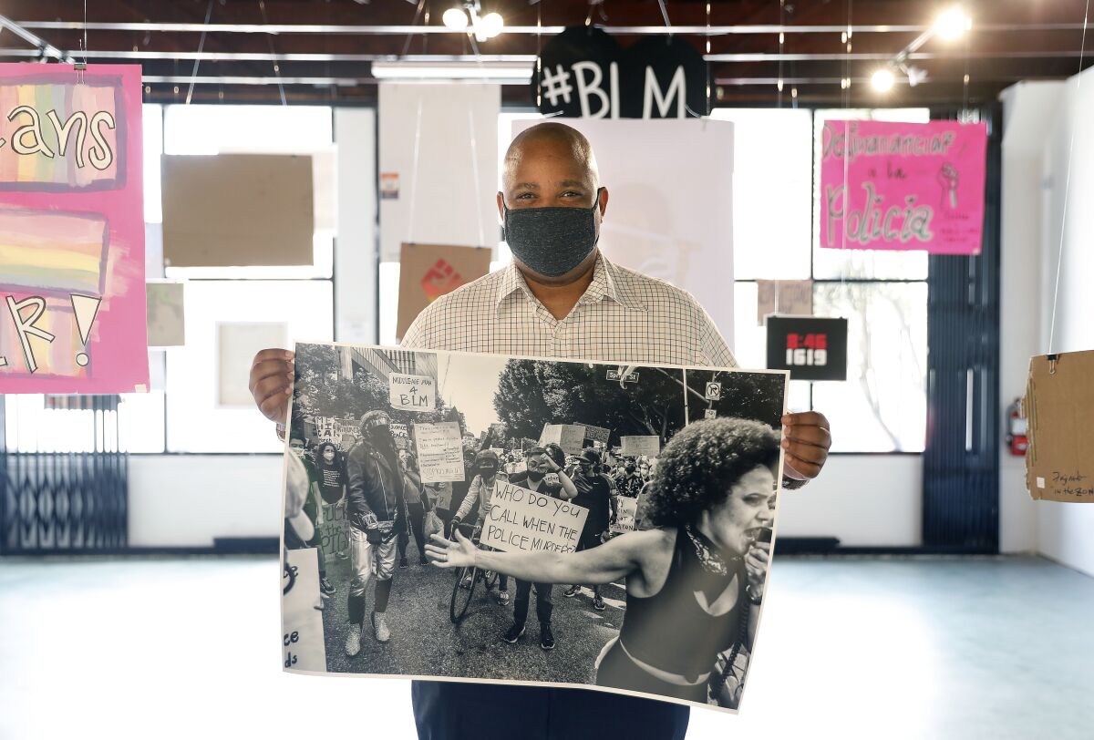 Photographer Adrian White holds a photograph of a protest at SoLA Contemporary.