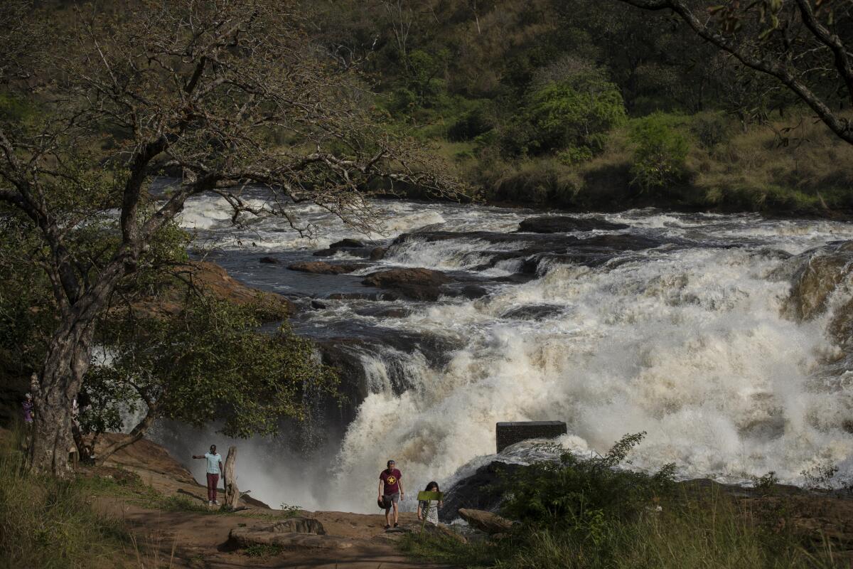 Tourists walk at the top of the waterfalls in Murchison Falls National Park, northwest Uganda, on Feb. 22, 2020. The East Africa Crude Oil Pipeline, a controversial oil project that would connect oilfields in the park to a port in Tanzania is in breach of global environmental and human rights guidelines for banks, according to a new report by Inclusive Development International on Tuesday, July 5. (AP Photo)