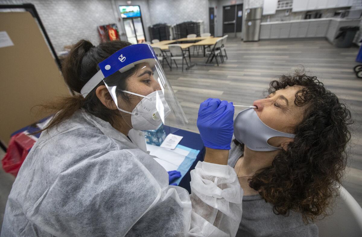 A medical worker uses a nasal swab to give a school employee a coronavirus test.