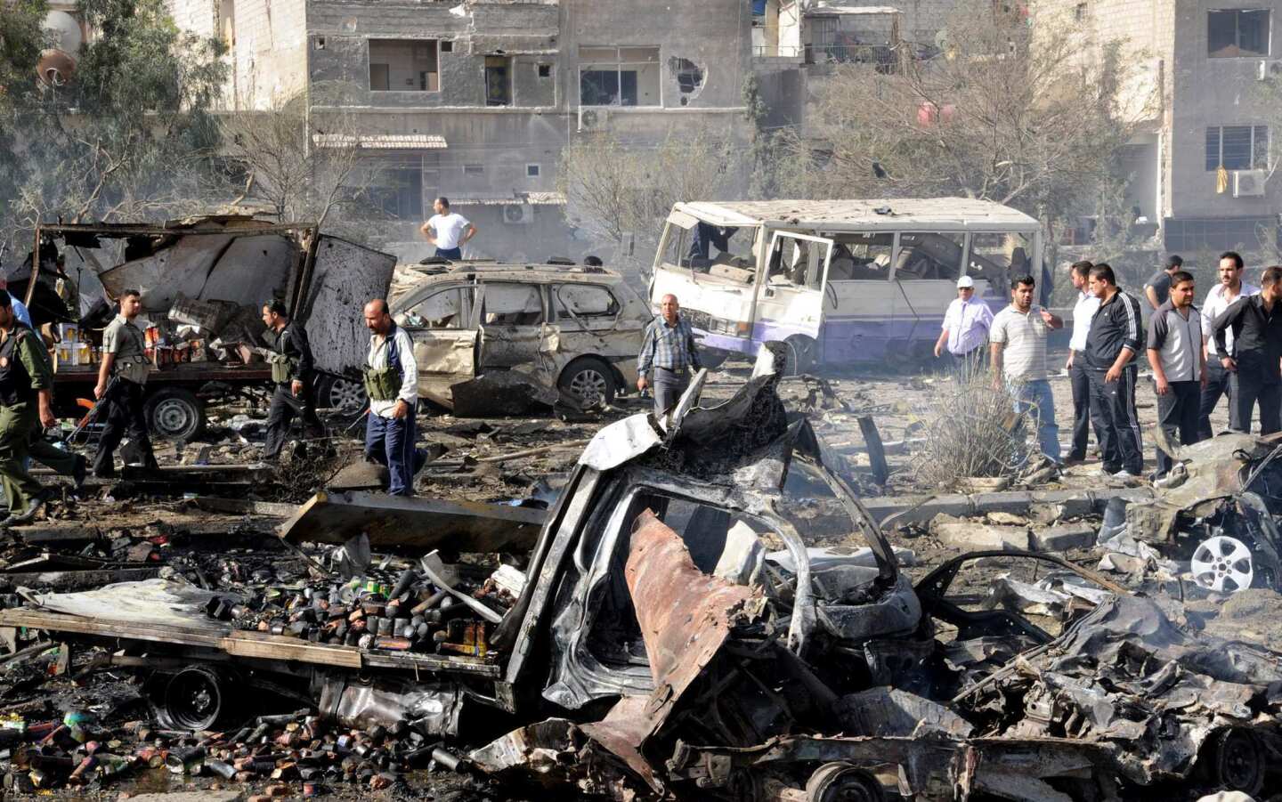 Security forces inspect the site of twin blasts in Damascus. Two powerful blasts struck during morning rush hour, killing scores, wounding dozens and prompting the UN observer chief to appeal for help to end the bloodshed ravaging Syria.
