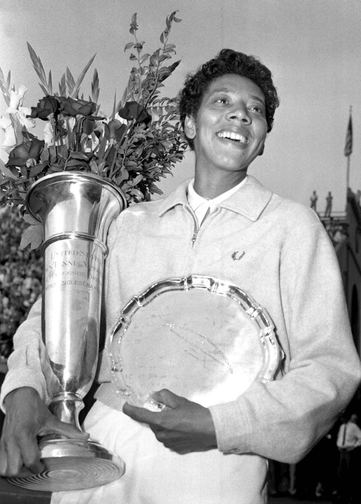 Tennis champion Althea Gibson smiles as she holds her trophies