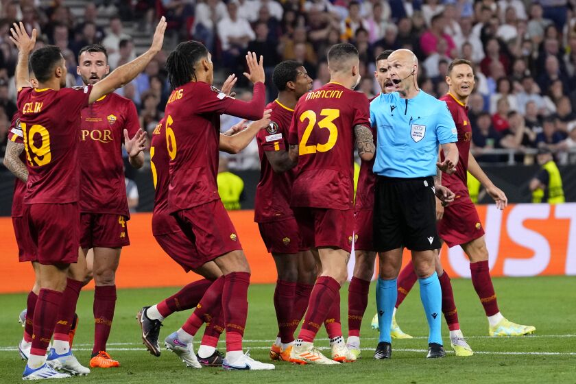 Roma players talk to Referee Anthony Taylor before he checks the VAR for a possible penalty during the Europa League final soccer match between Sevilla and Roma, at the Puskas Arena in Budapest, Hungary, Wednesday, May 31, 2023. (AP Photo/Petr David Josek)