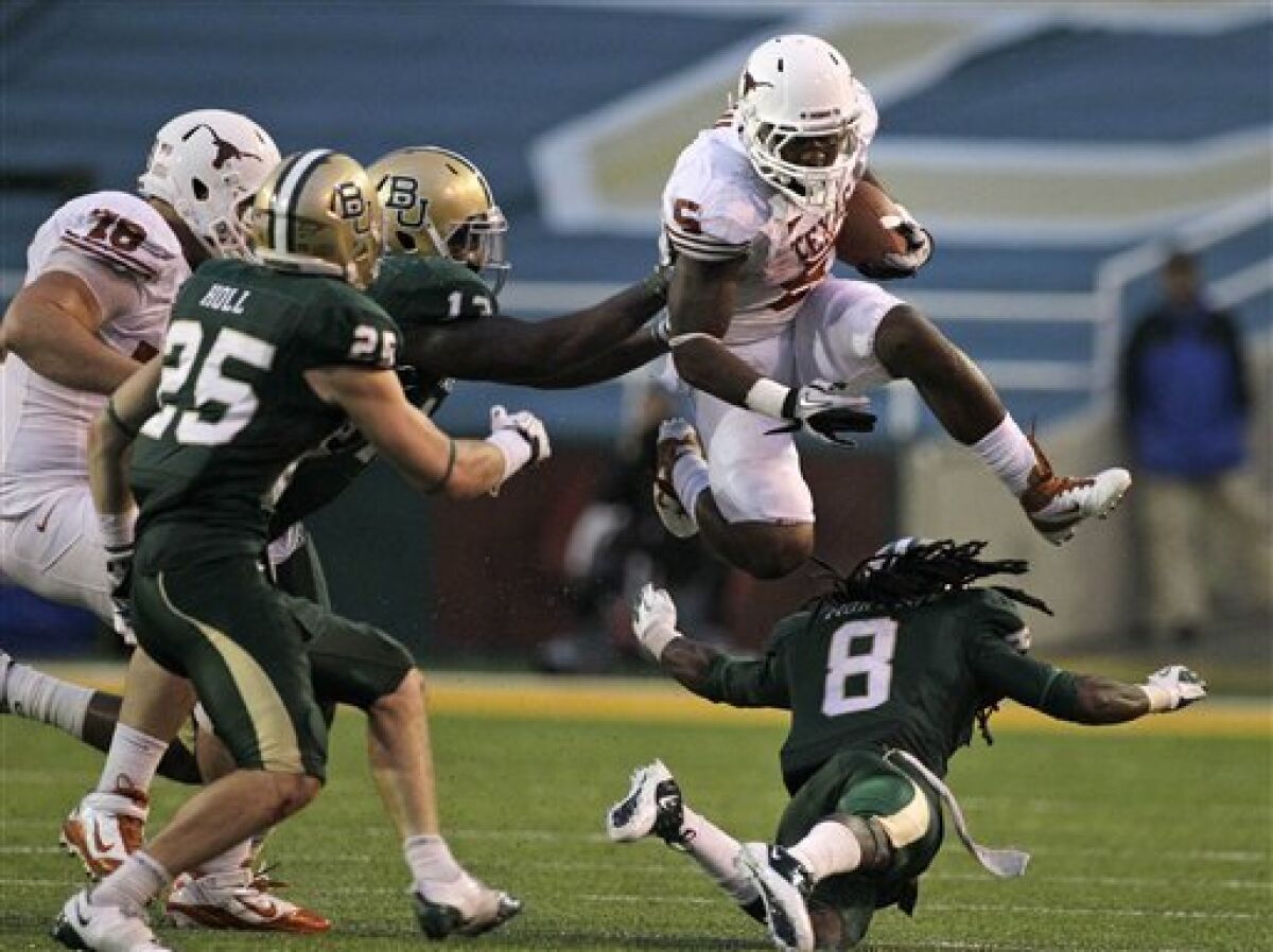 Texas running back Jeremy Hills (5) leaps over an attempted tackle by Baylor safety K.J. Morton (8) as Sam Holl (25), defensive tackle Tracy Robertson center rear, and Texas' David Snow (78) look on during the second half of an NCAA college football game Saturday, Dec. 3, 2011, in Waco, Texas. Baylor won 48-24. (AP Photo/Tony Gutierrez)