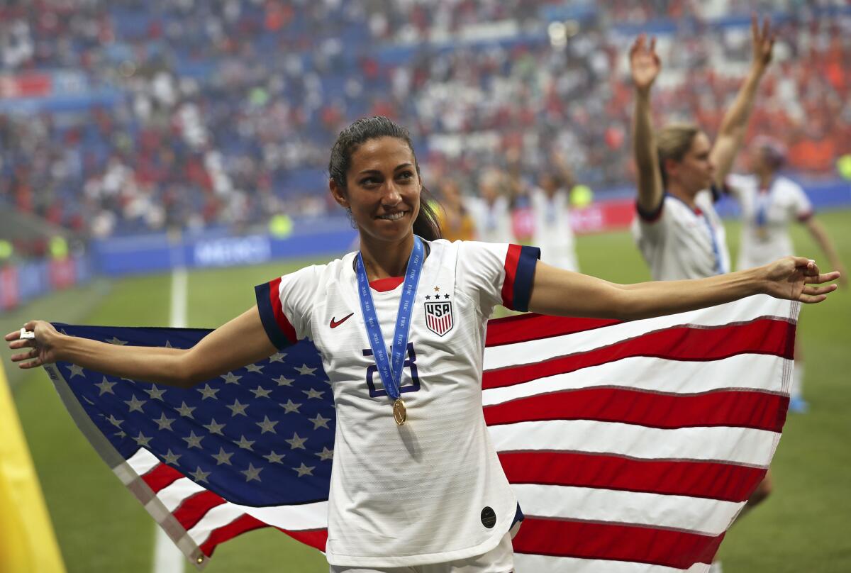 Christen Press celebrates winning the Women's World Cup final in 2019 while draped in an American flag