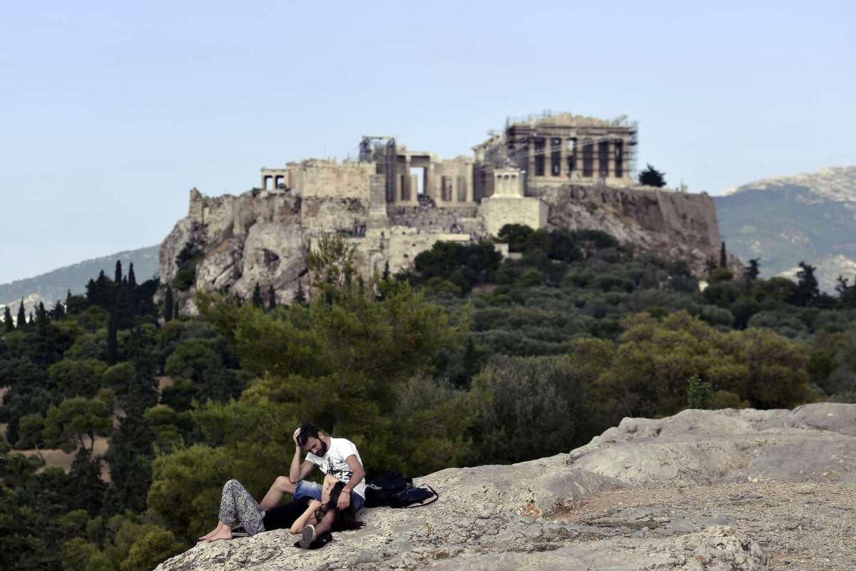 A couple rests on the Pnyx hill near the Acropolis in Athens on Friday while Greek officials were still wrangling with creditors on a bailout program extension to avert a default that looms in four days.
