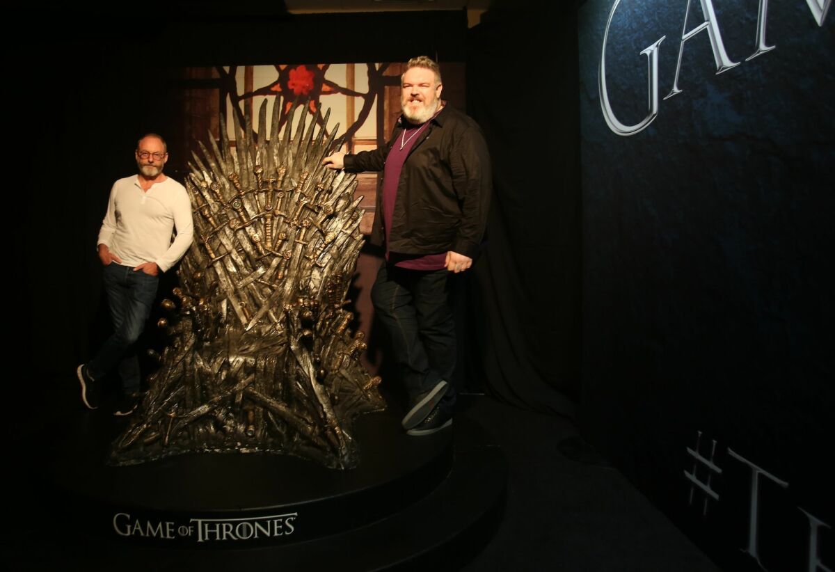 Liam Cunningham, aka Ser Davos, and Kristian Nairn, aka Hodor, stand beside the throne at the Game of Thrones exhibit.