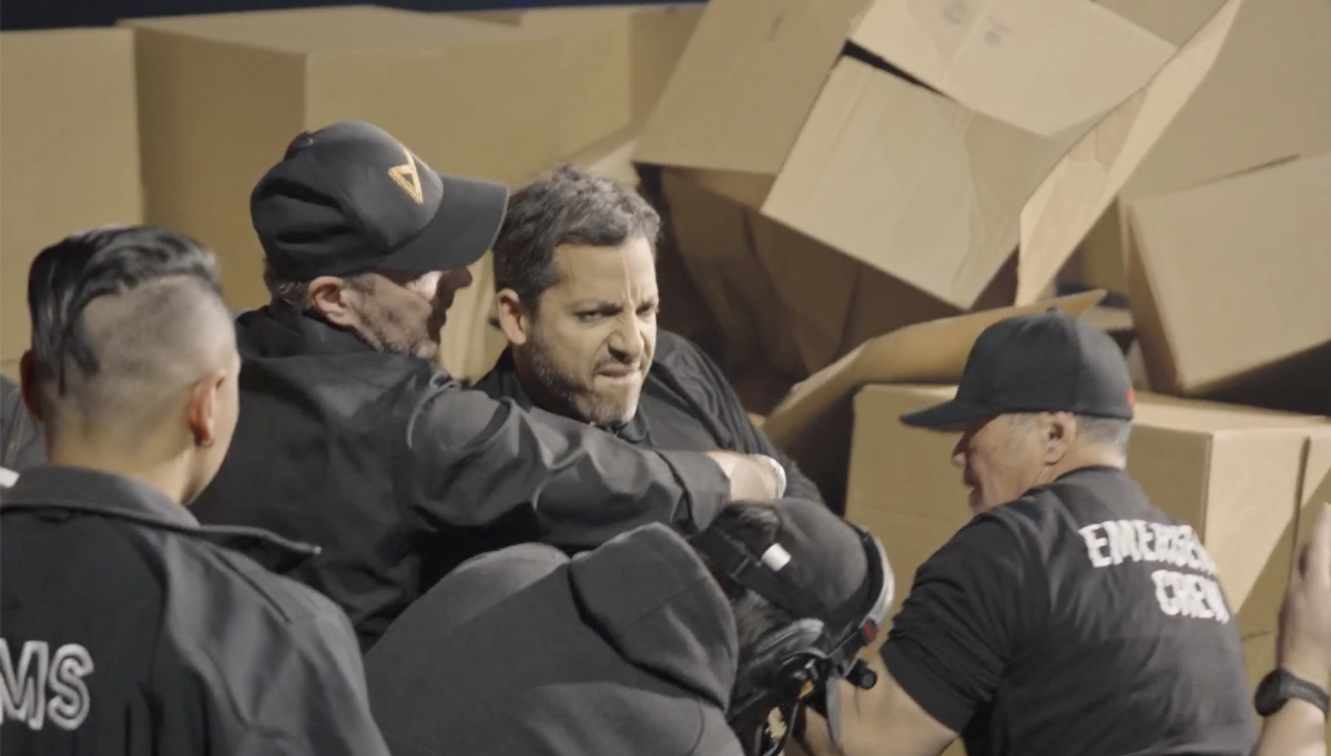 A man is surrounded by his medical team in front of pile of boxes moments after dislocating his shoulder during a stunt.