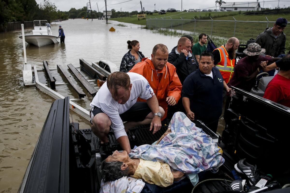 Rescuers move Paulina Tamirano, 92, from a boat to a truck bed as people evacuate from rising waters in Houston. (Michael Ciaglo / Houston Chronicle)