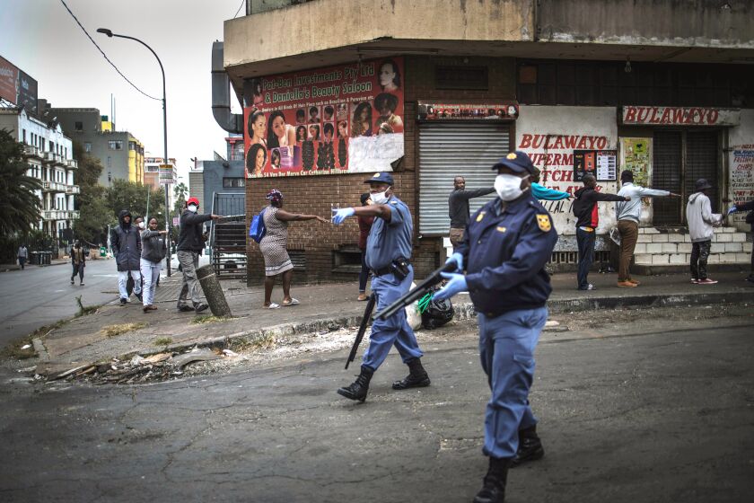SOUTH AFRICA: South African police officers enforce social distancing as they make shoppers stretch their arms in front of them to ensure that they are at least one metre apart from one another while they queue outside a supermarket in Hillbrow, Johannesburg, South Africa.