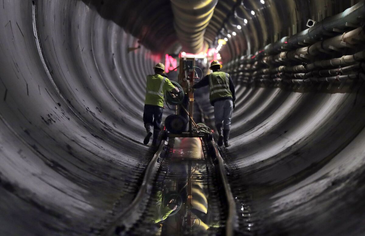 FILE - Tunnel workers push equipment up a rail track to a machine boring a 2.5-mile bypass tunnel for the Delaware Aqueduct in Marlboro, N.Y., on May 16, 2018. A long-planned temporary shutdown of a leaking aqueduct that supplies about half of New York City's drinking water will be pushed back a year, giving officials more time to prepare for the months-long closure. (AP Photo/Julie Jacobson, File)