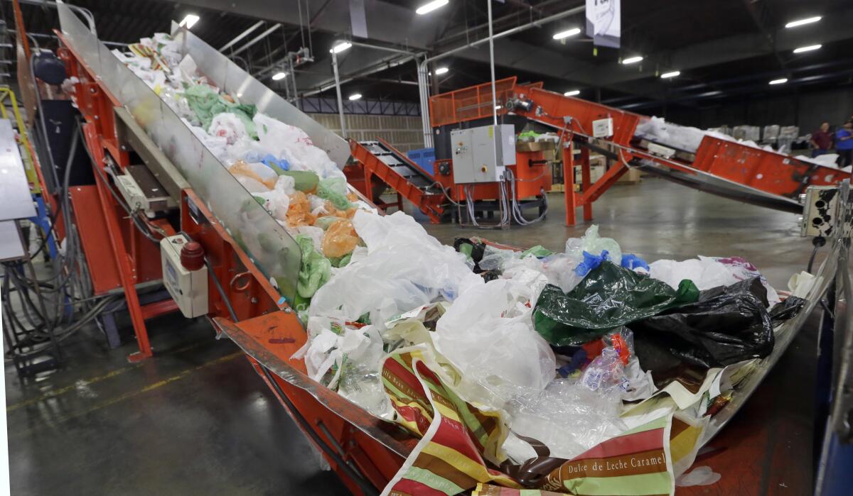 Conveyors carry mixed plastic into a device that will shred them at a plastics recycling plant.