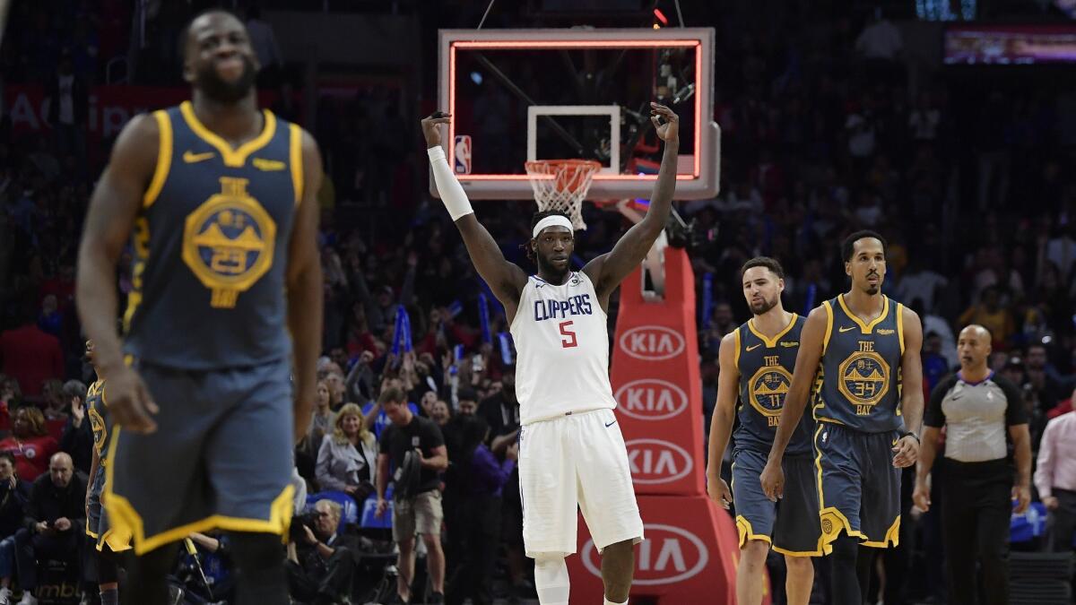 Clippers forward Montrezl Harrell, center, celebrates as time runs out in overtime as Golden State Warriors forward Draymond Green, left, guard Klay Thompson, second from right, and guard Shaun Livingston walk off the court.