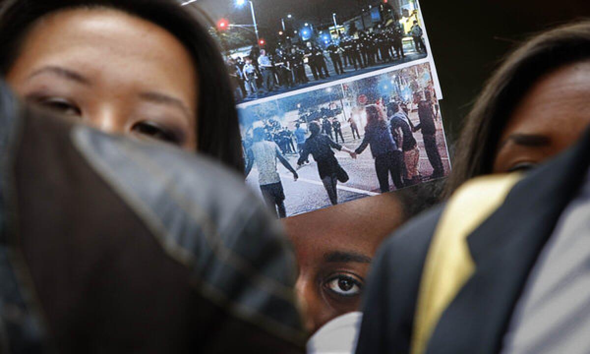 During a protest at USC, a student holds up photographs of the LAPD response to a party Saturday night.