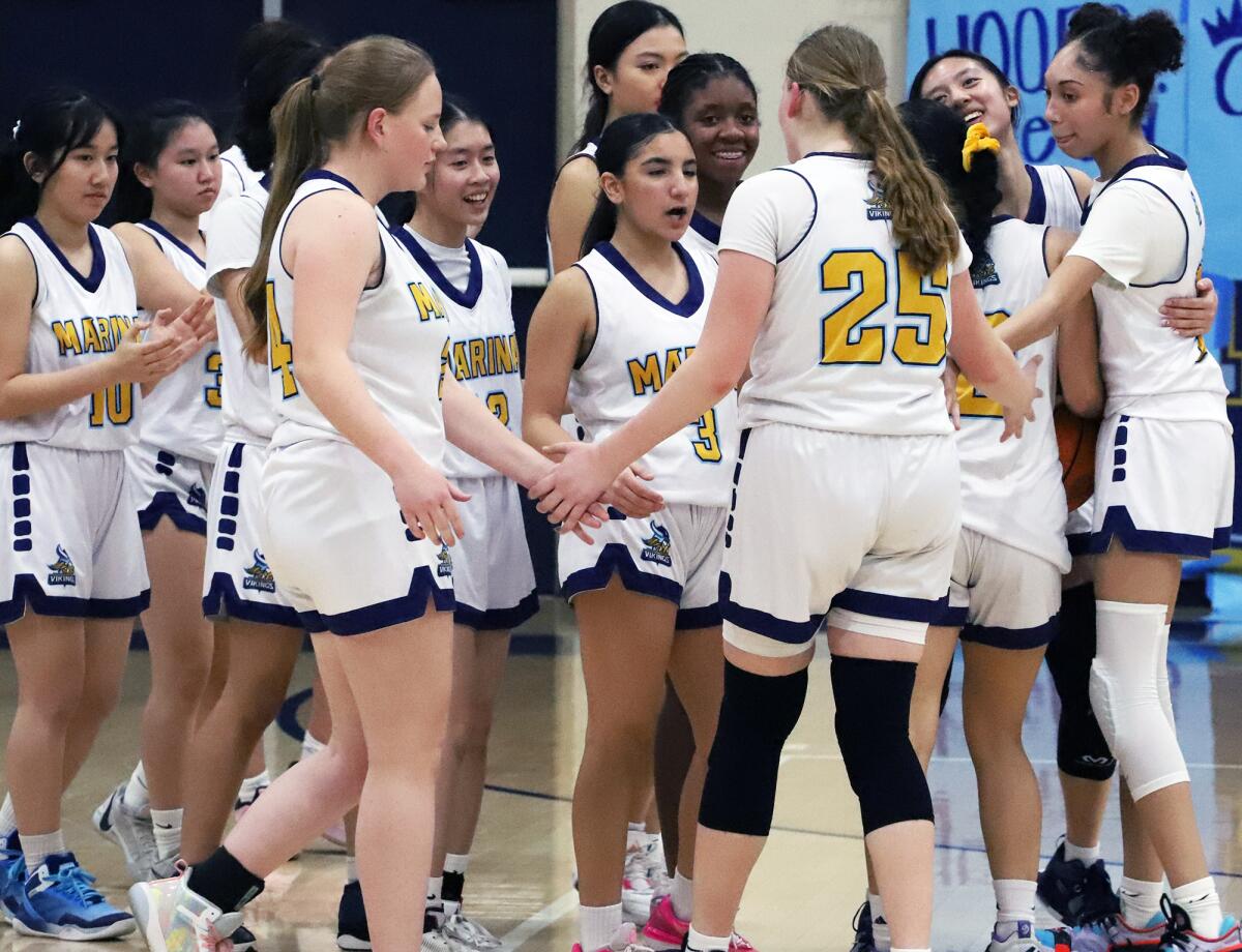 The Marina girls' basketball team celebrates a win over Huntington Beach to clinch the Wave League championship on Monday.