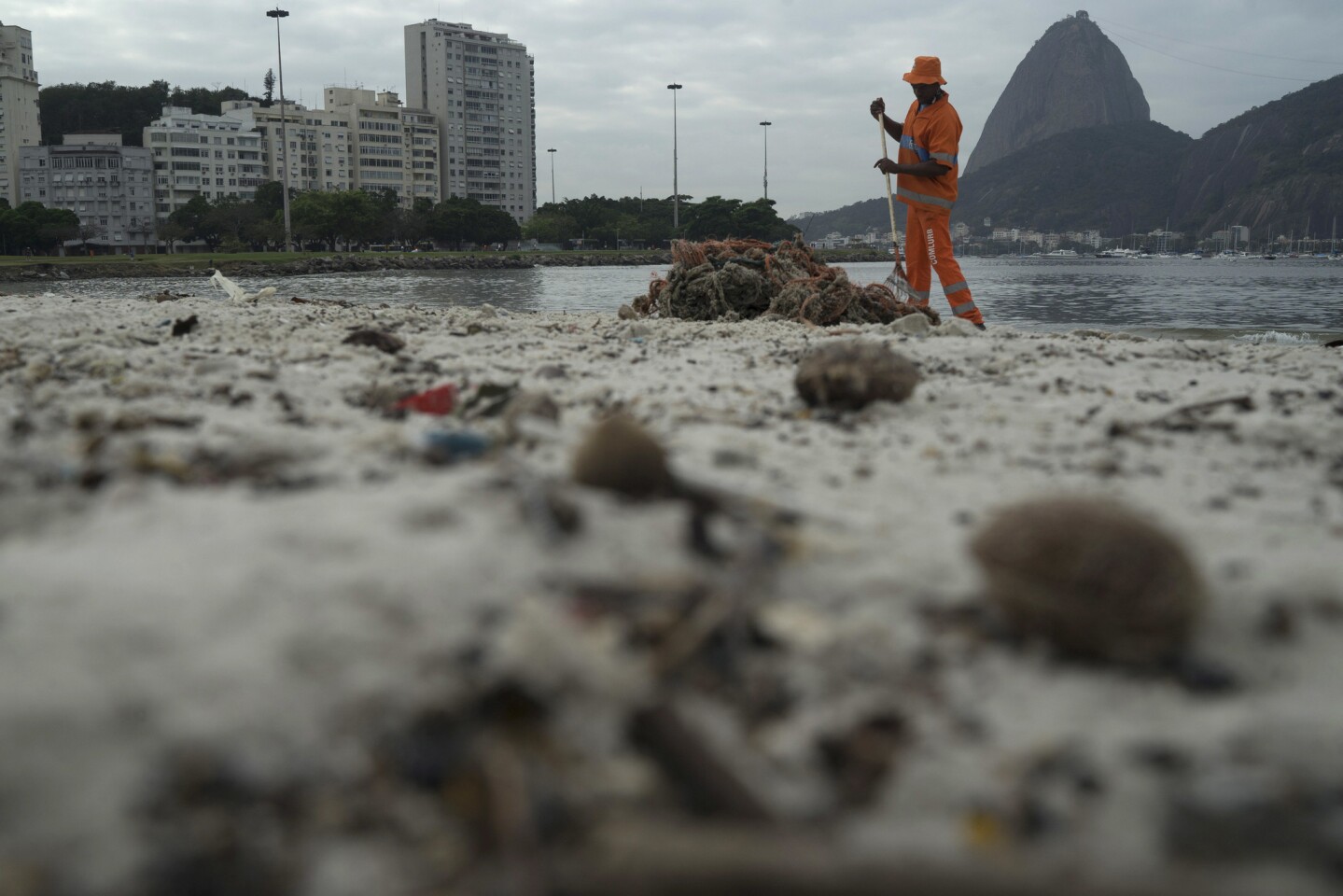 A worker removes trash from Botafogo beach next to the Sugarloaf Mountain and the Guanabara Bay in Rio de Janeiro. Just days ahead of the Olympic Games the waterways of Rio are as filthy as ever, contaminated with human sewage teeming with dangerous viruses and bacteria, according to a 16-month-long study commissioned by the Associated Press.