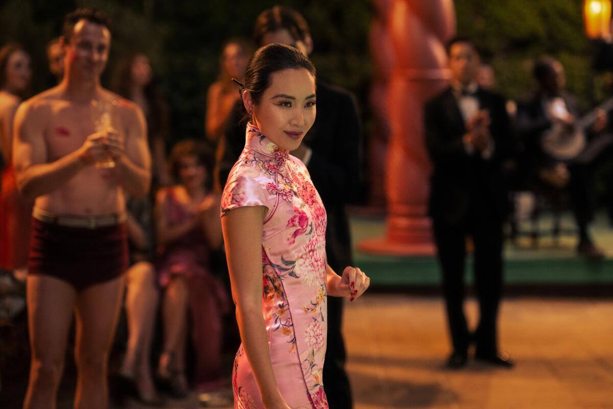 A woman at a party wears a pink cheongsam dress.