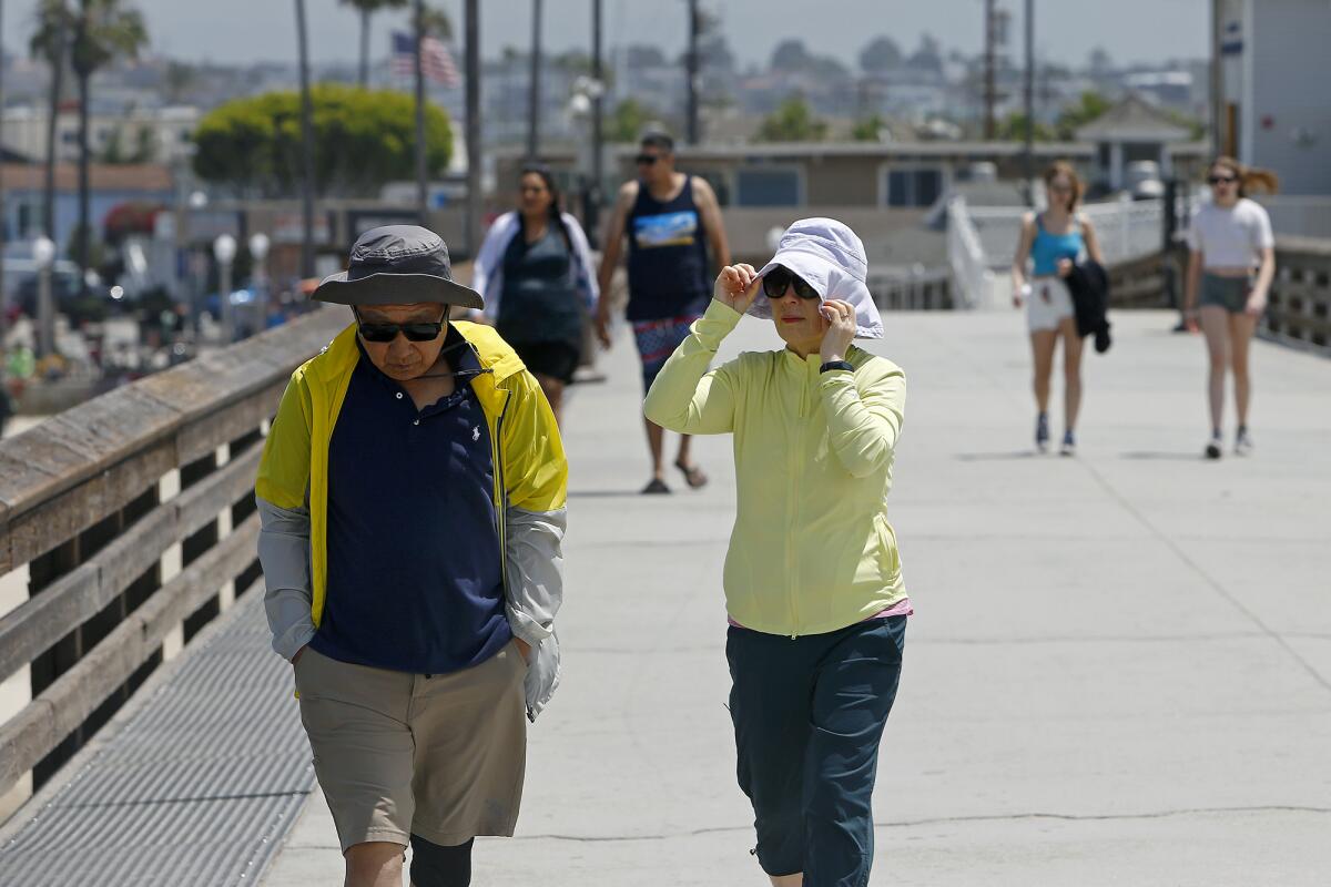 A woman holds onto her cap as heavy winds blow in from the coast.