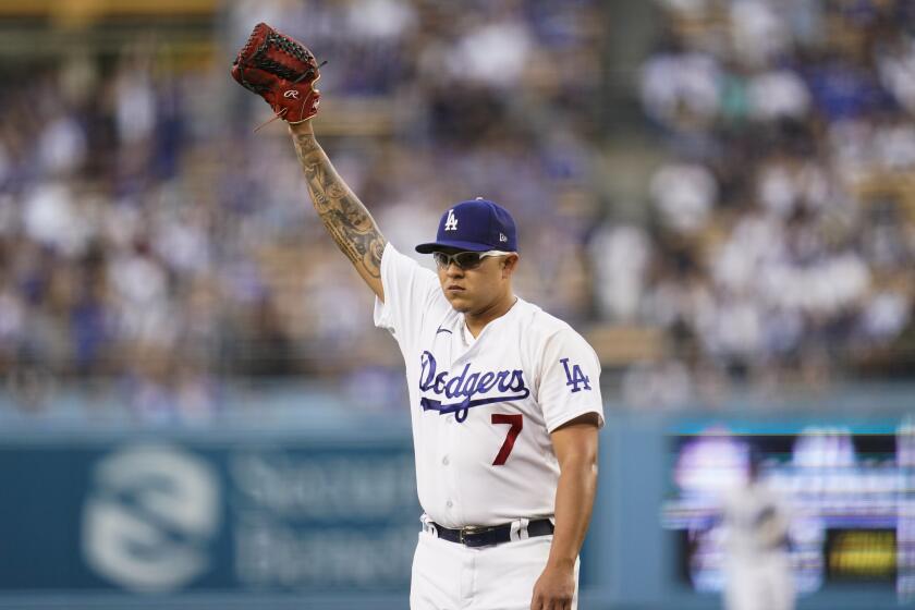 The Dodgers' Julio Urías raises his glove as he walks off the mound after the top of the first inning Oct. 2, 2021.