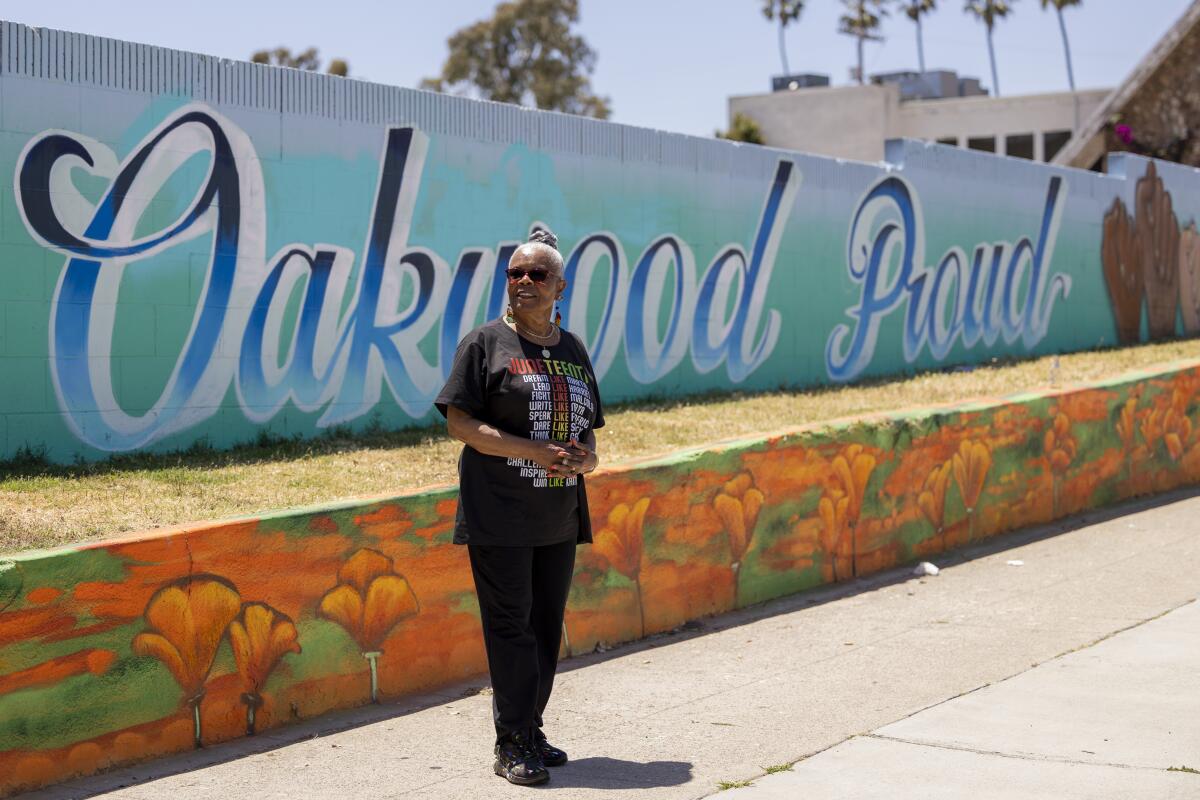 Naomi Nightingale stands in front of a sign that says Oakwood Proud.