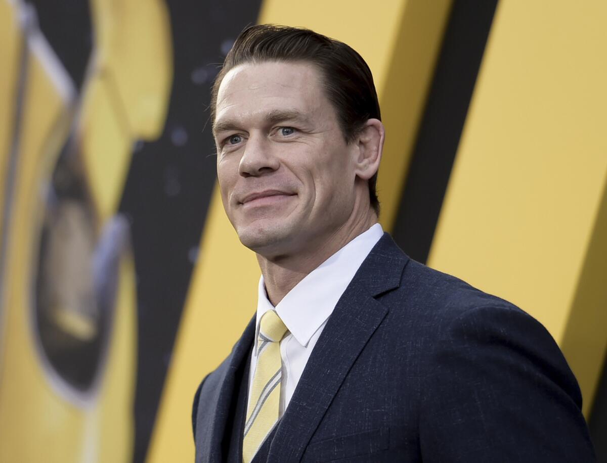 John Cena in a dark suit and striped yellow tie