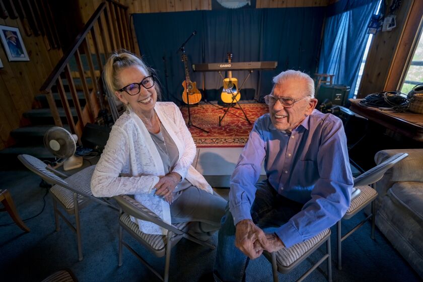 Lakeside, CA - September 20: At at his home on Tuesday, Sept. 20, 2022 in Lakeside, CA., Jimmy Duke and Linda Piro-Duke sit next to their living room concert venue where the couple has hosted living room concerts since 1998. The concert scheduled for September 25th will be their 185th and last concert from their home. (Nelvin C. Cepeda / The San Diego Union-Tribune)