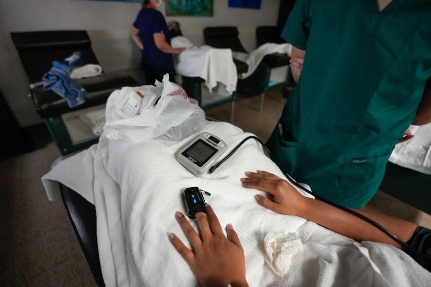 A medical student, right, and nurse, back, monitor women as they rest before and after getting abortions