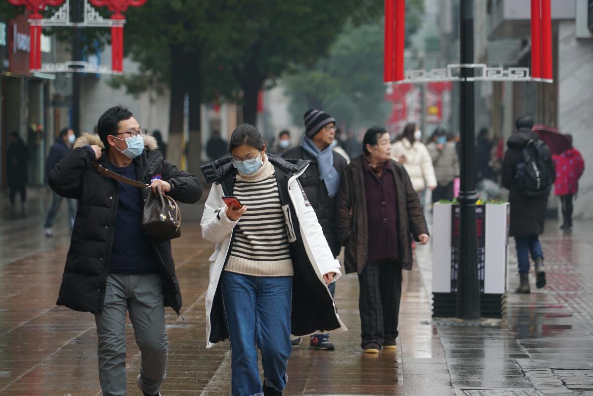 Masked pedestrians walk down a shopping street in downtown Wuhan, China. The new coronavirus outbreak, as of Jan. 31, had resulted in at least 213 people dead and more than 9,709 cases confirmed in mainland China, as the virus spreads globally.