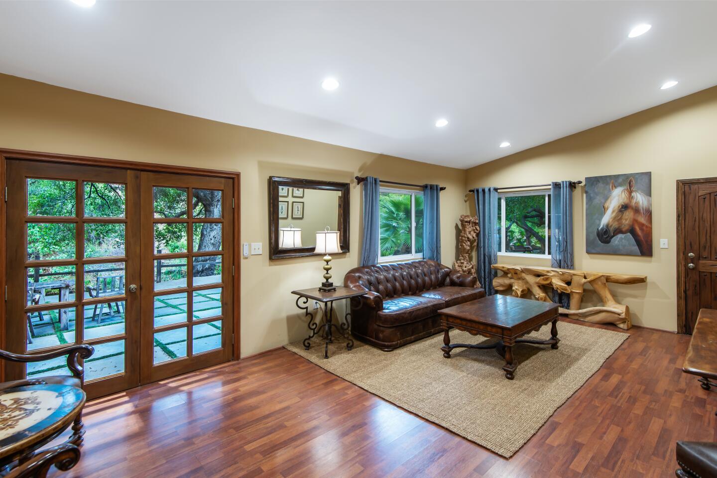 Double wood doors in a living area with wood floors lead onto a deck.
