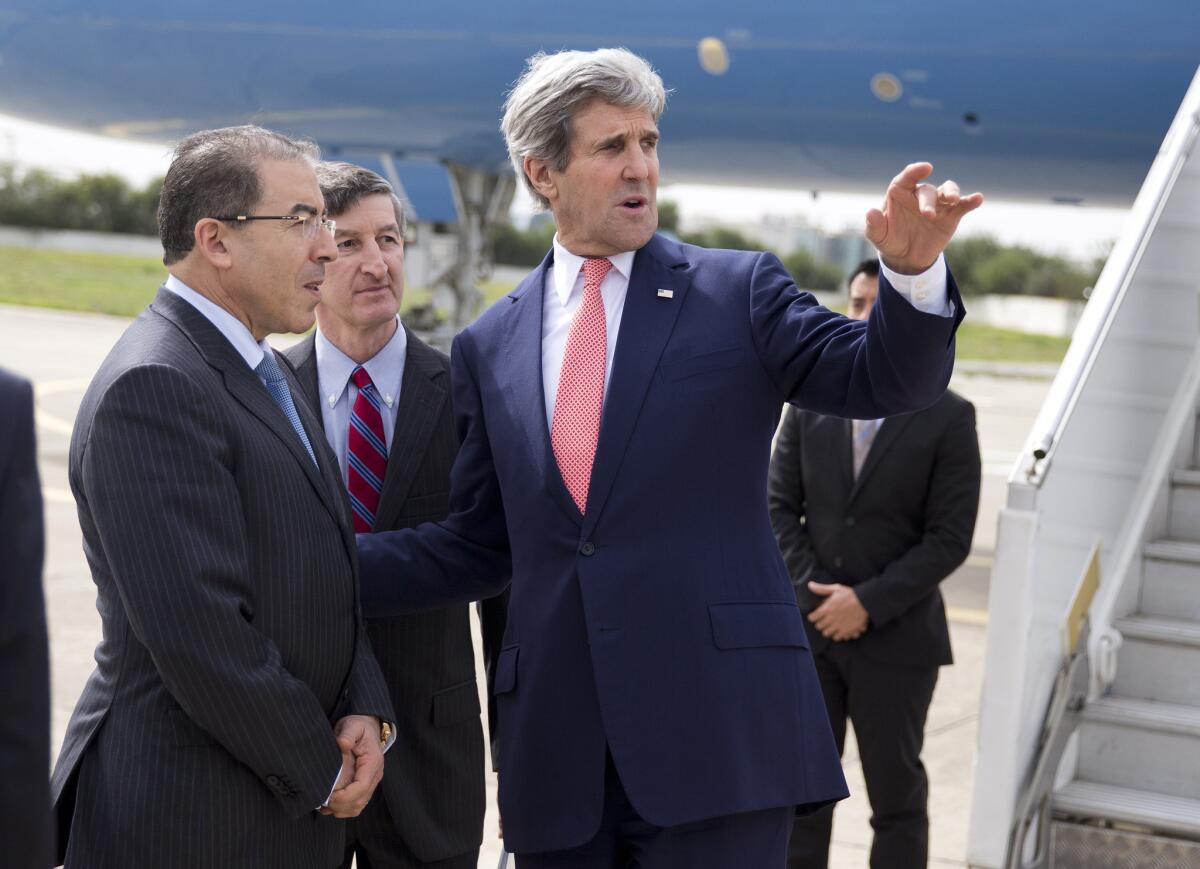 Secretary of State John Kerry, right, talks with Tunisian Foreign Minister Mongi Hamdi, left, and U.S. Ambassador Jake Walles after arriving at El Aouina Air Base in Tunis.