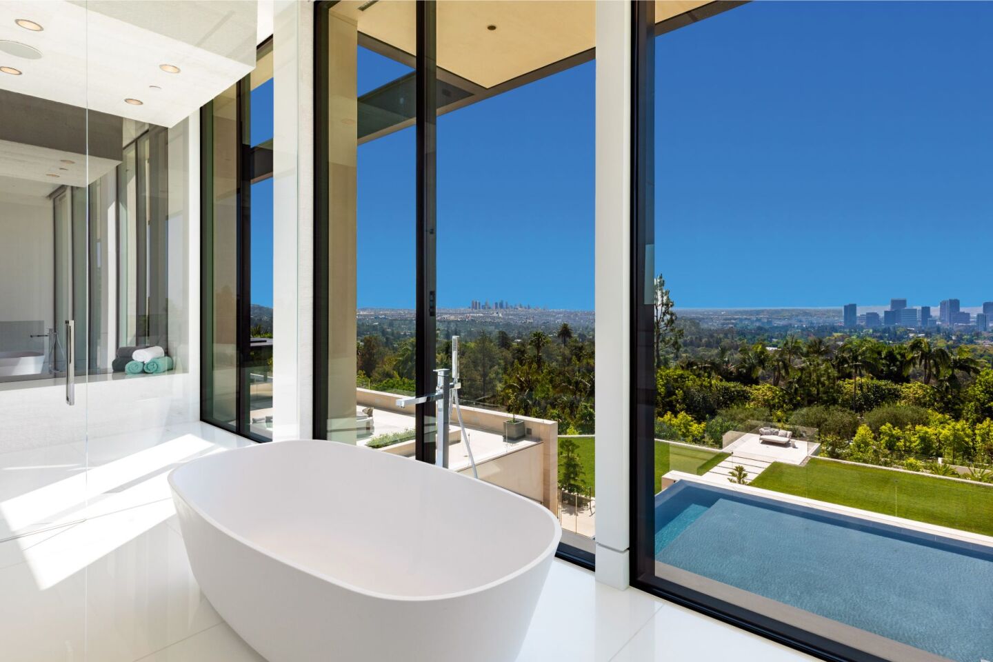 The bathroom has a bathtub that looks out on the property, trees and sky.