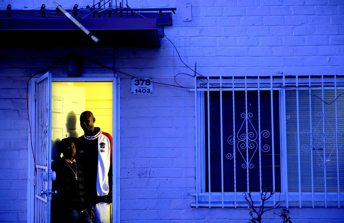 Jeff Littrel and his son Malik stand in the doorway of their home in Ramona Gardens. "He's got more love than me around here," Littrel says. "I can pretty much go wherever, but because of him. They know I'm Malik's daddy!"