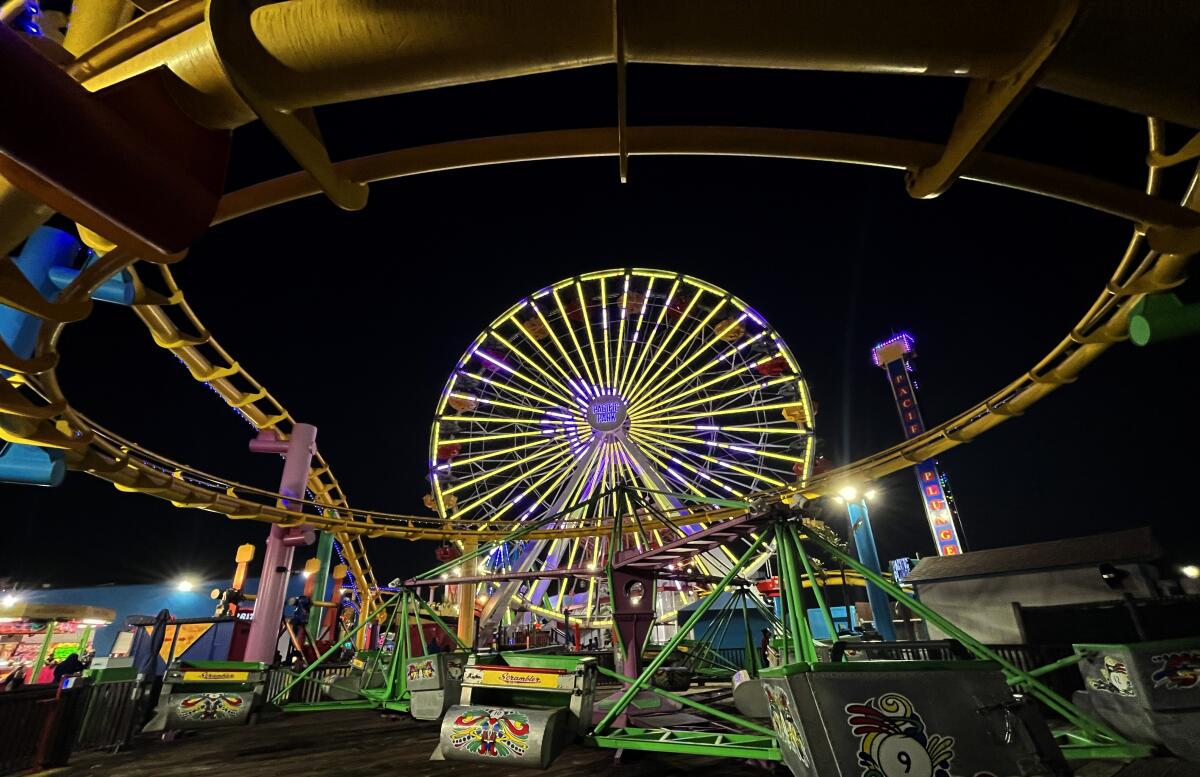 A Ferris wheel is shown lighted up amid carnival rides.