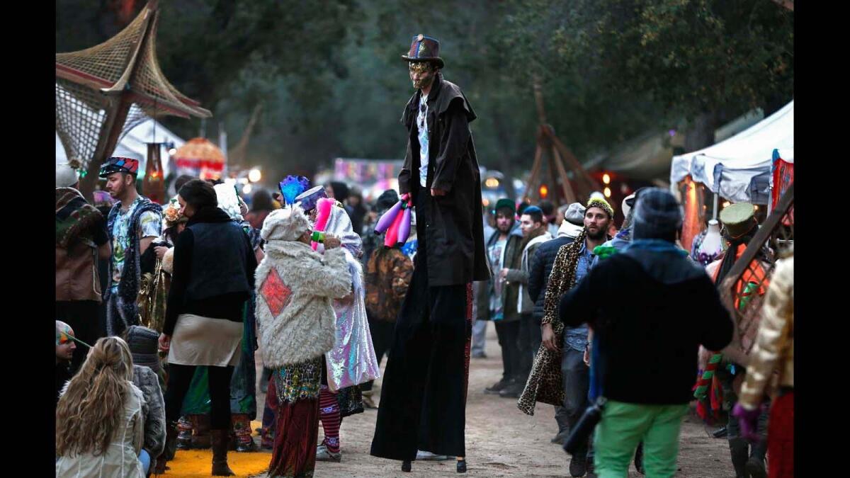 Costumed concertgoers crowd the vendor and food path at the Desert Hearts music festival.
