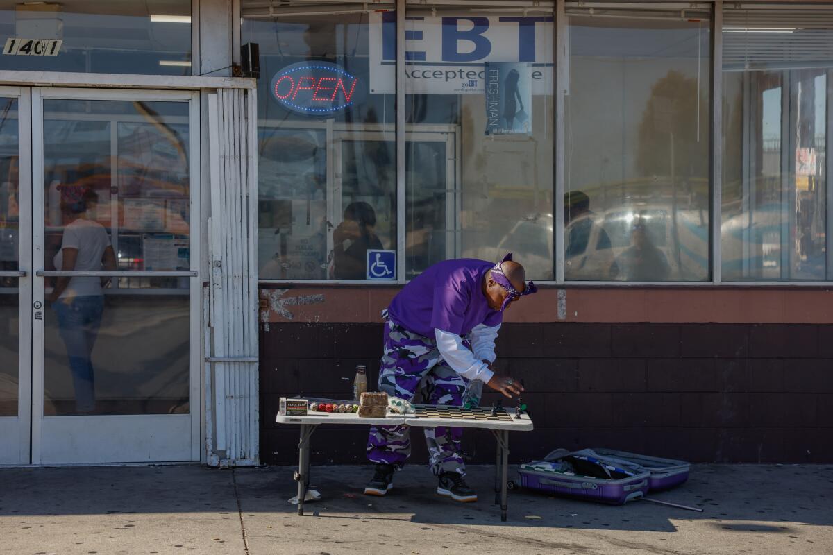 Vincent Hubbard leans over a folding table to make a chess move outside a Louisiana Fried Chicken.
