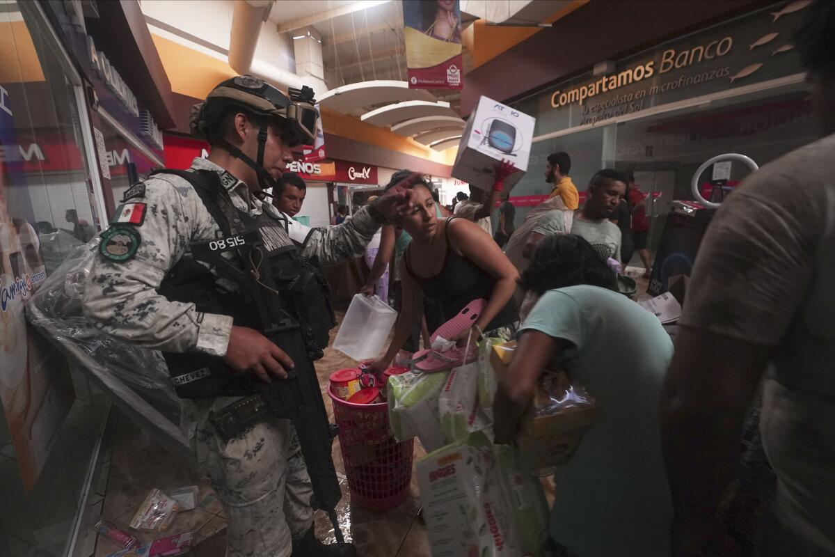 Un militar de la Guardia Nacional mexicana intenta impedir que personas se lleven productos