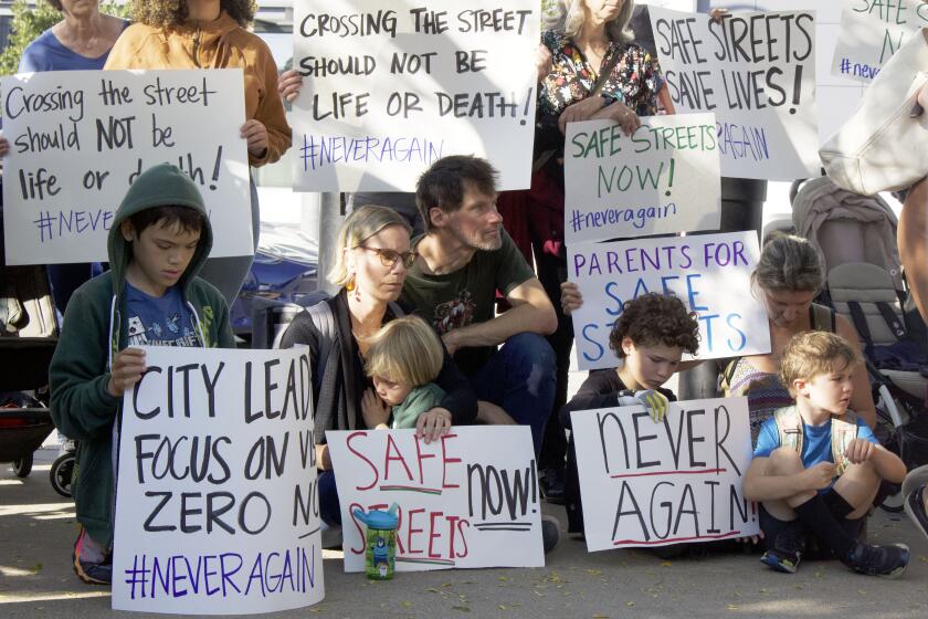 People hold signs that read “never again” at a rally in the Mission Bay district in San Francisco on Aug. 22, 2023.