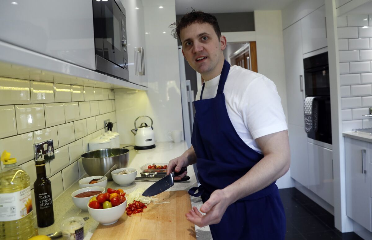 Jon Watts, demonstrates his cooking skills for the Associated Press by making a prawn linguini at a friends kitchen in Codicote, Welwyn, England, Thursday, April 15, 2021. Jon Watts was 18 years old when he woke up in a prison cell and decided he had to change. He enrolled in every course he could find, from mathematics to business. But he says it was a program founded by Prince Philip, the Duke of Edinburgh, that gave him a “passion for food” and a career as a chef when he got out of prison 3 1/2 years later. (AP Photo/Alastair Grant)
