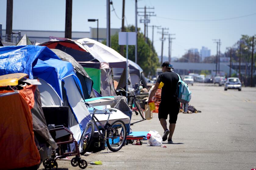 San Diego, CA - May 12: On Thursday, May 12, 2022 in San Diego, CA., Billy Mroczka walks past several tents at a homeless encampment after receiving a fresh supply of new needles and sterile alcohol pads. Mroczka a drug user plans on meeting with Tara Stamos-Buesig at his tent so that she can test samples of his drugs to determine if it contains Fentanyl, heroin or Ketamine Stamos-Buesig is the executive director of On Point, a mobile syringe service and harm reduction program in San Diego. (Nelvin C. Cepeda / The San Diego Union-Tribune)