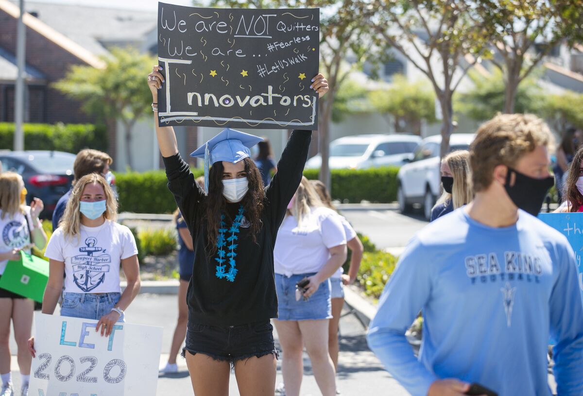 Ava Yacoel, 18, a senior at Corona del Mar High School, holds up a sign protesting the Newport-Mesa Unified School District's decision to not hold in-person graduation ceremonies this year because of the COVID-19 pandemic.