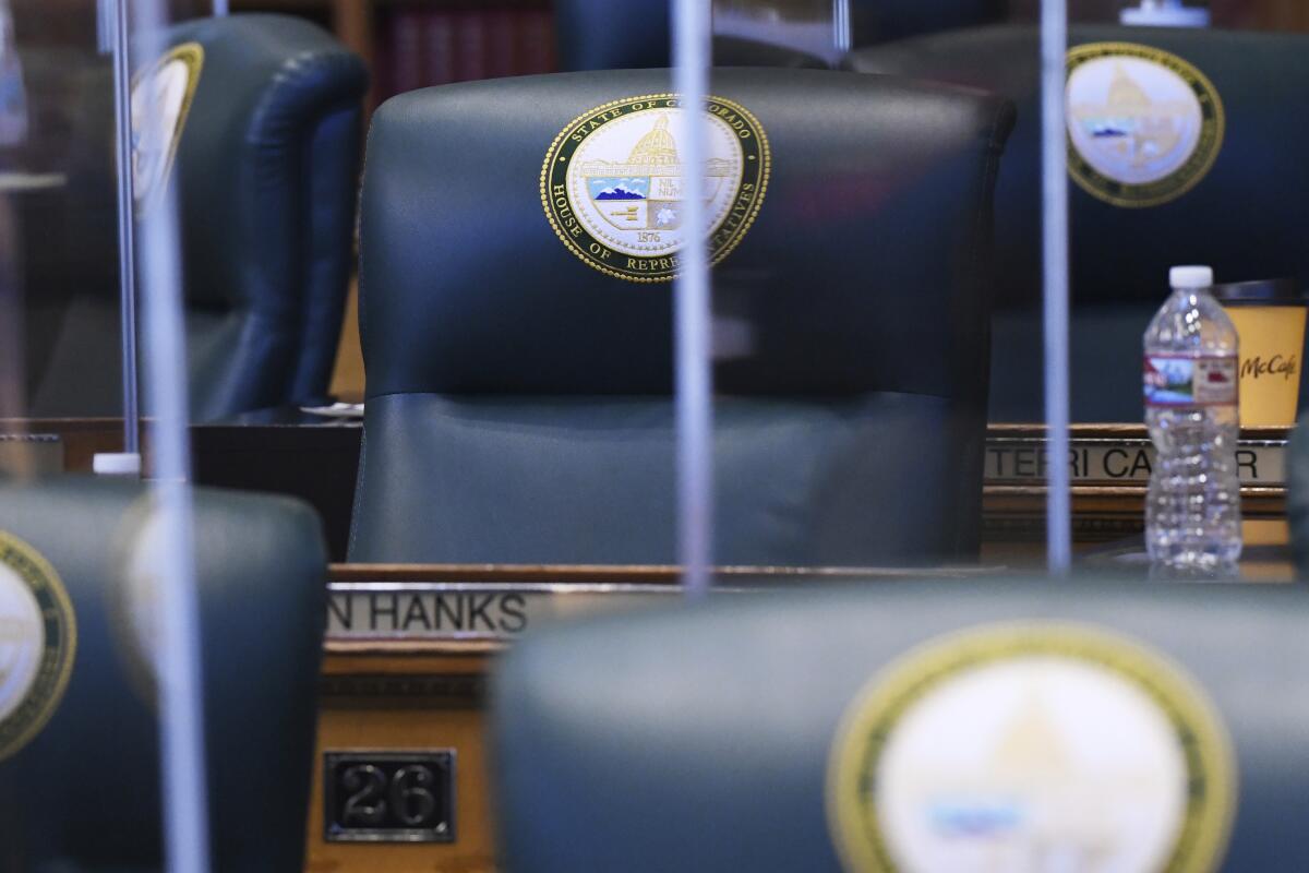 The desk of Rep. Ron Hanks, R-Penrose, sits empty during second day of the 73rd General Assembly of the Colorado State Legislature, Thursday, Jan. 14, 2021, in Denver. Democrats in Colorado have condemned the Republican lawmaker for joking about lynching before saying a 18th century policy designating a slave as three-fifths of a person “was not impugning anybody’s humanity." (Hyoung Chang/The Denver Post via AP)