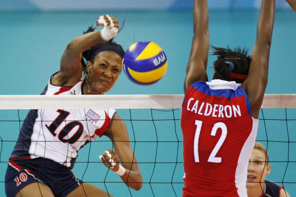 FILE - USA's Kim Glass, left, jumps for the ball with Cuba wing spiker Rosir Calderon during a women's Volleyball match at the Olympics in Beijing on Aug. 11, 2008. A former Olympic volleyball player was attacked Friday, July 8, 2022, in downtown Los Angeles when a man threw a metal object at her face in an assault that fractured bones in her face and left one of her eyes swollen shut, the athlete said in videos posted to social media. Glass, a silver medalist at the 2008 Beijing Olympics, had been leaving a lunch on Friday afternoon when she saw a man run up with something in his hand. (AP Photo/Luca Bruno, File)