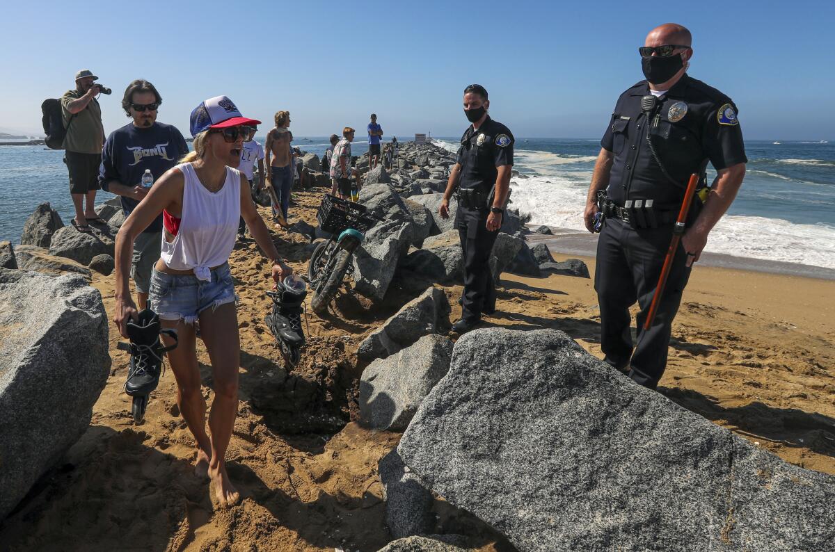 Two police officers in masks oversee a group of people leaving the beach