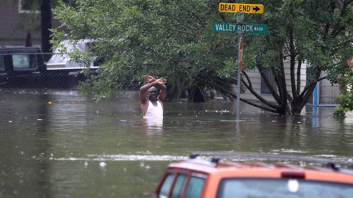A man waves down a rescue crew after his neighborhood was inundated with flooding from Tropical Storm Harvey.