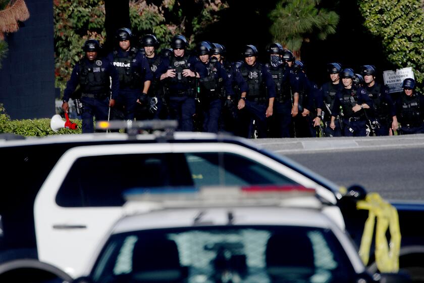 LOS ANGELES, CALIF. - JULY 24, 2022. LAPD officers and Sheriff's deputies stage at the entrance to Peck Park in San Pedro, where seven people were injured in a shooting on Sunday afternoon, July 24, 2022. (Luis Sinco / Los Angeles Times)