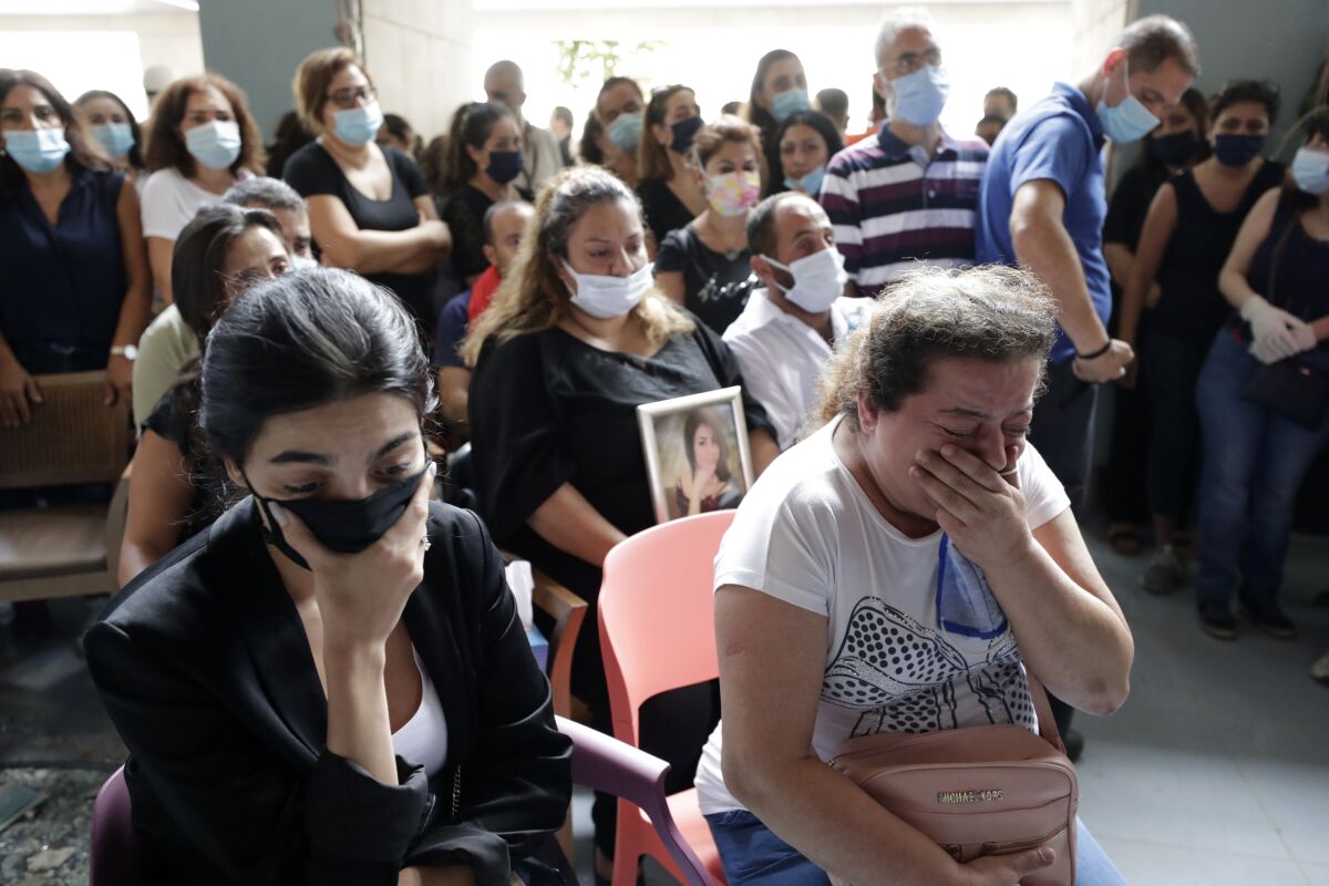 Families, friends and colleagues of four nurses of the Saint George Hospital University Medical Center, who died in the Tuesday explosion at the seaport of Beirut, attend a mass officiated by Greek Orthodox Metropolitan of the Archdiocese of Beirut, Elias Audi, in Beirut, Lebanon, Thursday, Aug. 6, 2020. (AP Photo/Hassan Ammar)