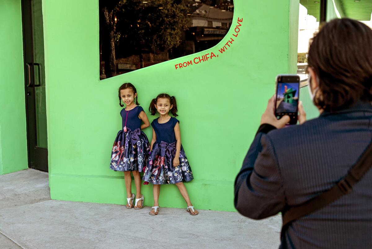Co-owner Humberto Leon taking a cellphone photo of his twin 7-year-old daughters 
